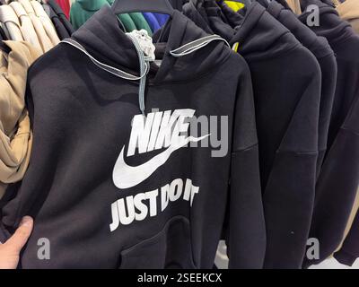 Black nike hoodie with just do it slogan displayed on hangers in clothing store. Stock Photo