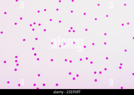 Pink glitter dots scattered on light lilac background. Top view. Stock Photo