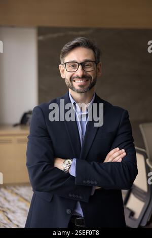 Smiling businessman staring at camera standing in modern office Stock Photo