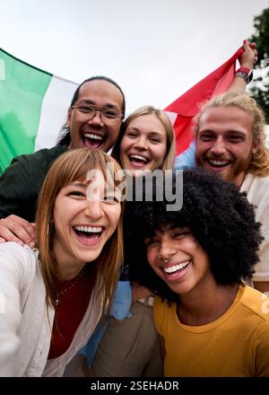 Happy multi-ethnic friends taking selfie with italian flag waving in the city center Stock Photo
