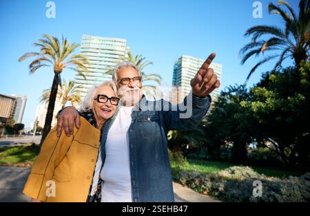 Senior couple pointing while visiting Barcelona city during vacation Stock Photo