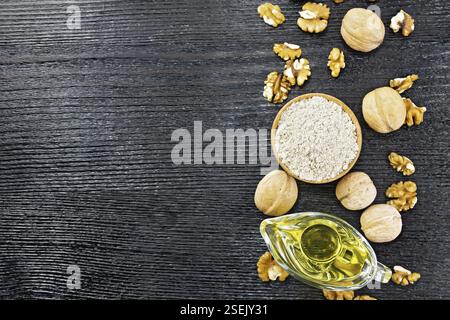 Frame from walnut flour in a bowl, oil in sauceboat and nuts on a dark wooden board background from above Stock Photo