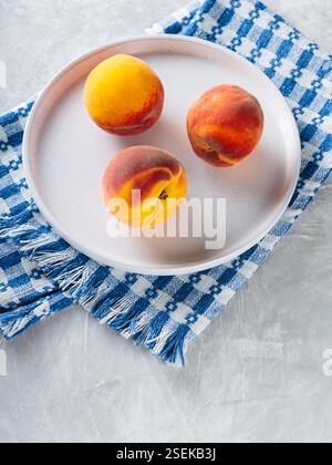 Fresh Peaches on White Plate with Blue White Checkered Napkin, Copy Space Stock Photo