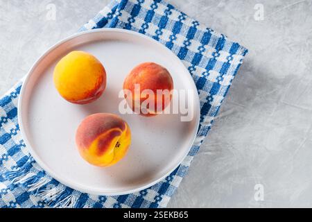 Fresh Peaches on White Plate with Blue White Checkered Napkin, Copy Space Stock Photo