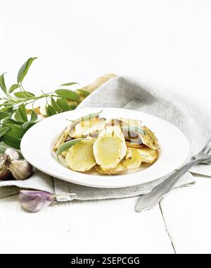 Baked parsnips with spices, garlic and sage in a plate on a towel against the background of light wooden board Stock Photo