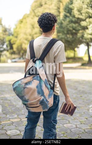Description: A student waiting on the sidewalk to be picked up from university, looking relaxed. Perfect for themes of student life, university experi Stock Photo