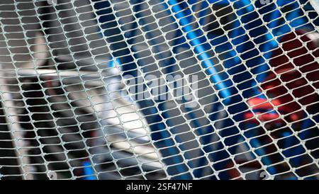 Close-up of a metal mesh fence with blurred abstract industrial background. Stock Photo