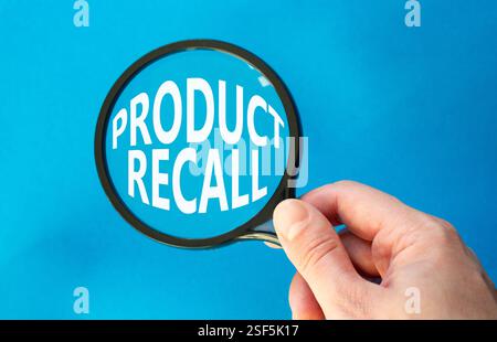 Product recall symbol. Concept words Product recall on magnifying glass. Beautiful blue background. Businessman hand. Business and Product recall conc Stock Photo