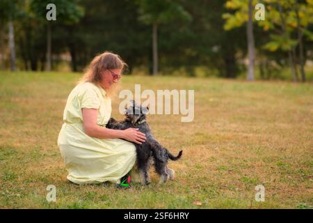 The mature female owner is taking her miniature dogs for a relaxing walk outdoors. Stock Photo