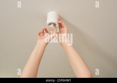 Hands installing or replacing a ceiling light fixture. Home lighting and interior maintenance concept. Stock Photo