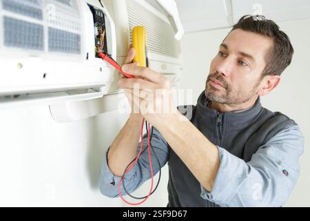 male electrician checking air conditioner with digital multimeter Stock Photo