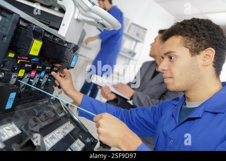 technician using a tablet to fix a printer Stock Photo