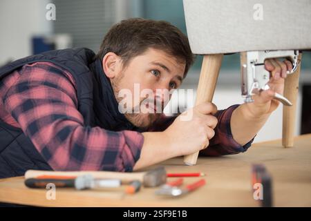 man puts together one part of sofa with stapler Stock Photo