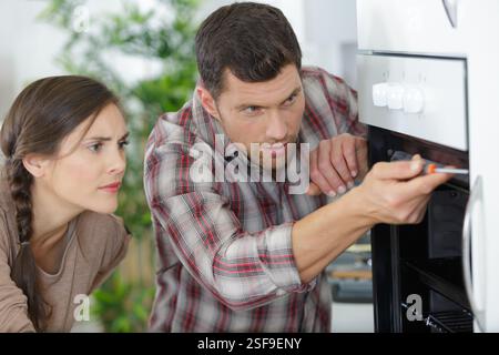 male worker installing oven for repairing in kitchen Stock Photo