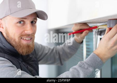service man installing window with screwdriver Stock Photo