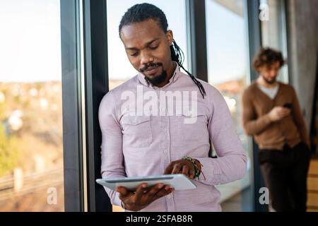 Smiling busy young African American business man, manager using tablet computer Stock Photo