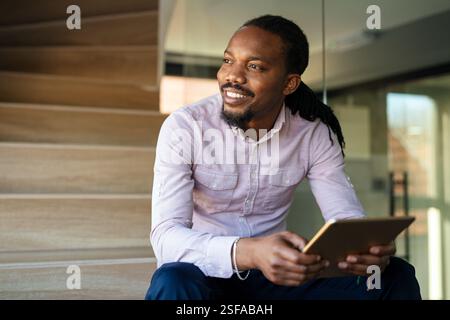 Relaxed smiling african american man holding digital tablet computer using apps Stock Photo