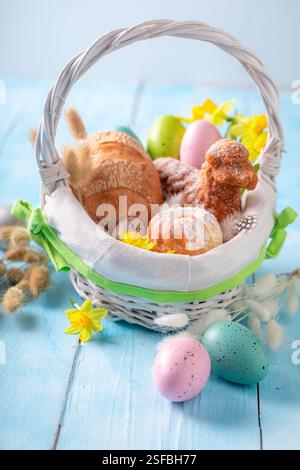 Colorful Easter basket with flowers, painted eggs and bread. Easter food for blessing in church. Stock Photo