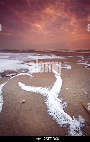 Icy sandy beach by Curonian Spit at sunset, Lithuania Stock Photo
