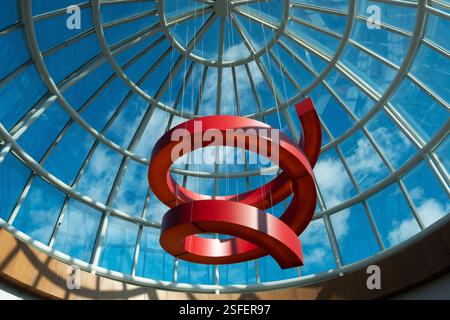 A red curved squiggle sculpture hanging from a dome in the Roosevelt Field Mall in Garden City, Long Island, New York. Stock Photo