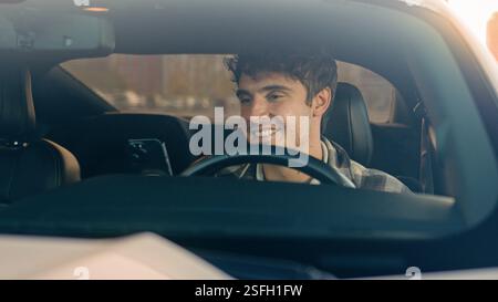 Happy smiling business man using phone apps in car urban driving lifestyle with mobile app technology smartphone in auto gps navigation. Cheerful male Stock Photo