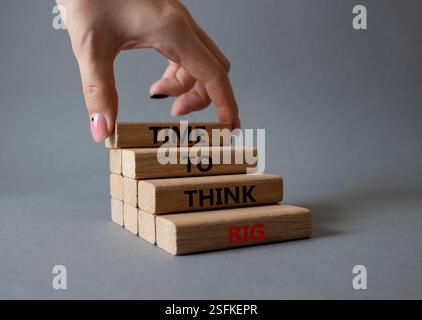 Time to think big symbol. Wooden blocks with words Time to think big. Beautiful grey background. Businessman hand. Business and Time to think big conc Stock Photo