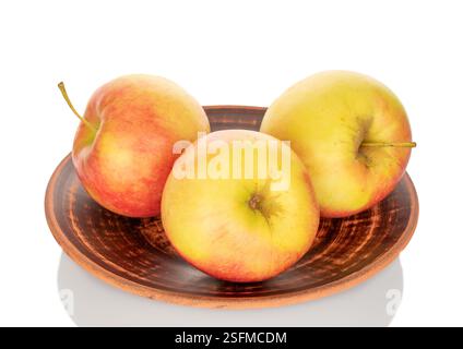 Three sweet apples on a clay plate, close-up, isolated on a white background. Stock Photo