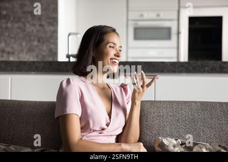 Smiling young 20s woman having call seated on couch Stock Photo