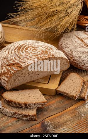 Freshly baked round loaf of rye bread with slices on rustic wooden table Stock Photo