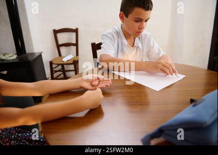 Children engaged in a collaborative classroom activity, focusing on solving problems together at a shared desk. Stock Photo