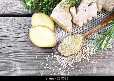 Ground ginger in a spoon, flakes and ginger root on burlap, spicy herbs on a wooden board background from above Stock Photo