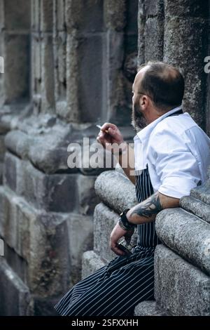 Porto, Portugal - December 28, 2024: A Portuguese waiter smoking during a break on the street Stock Photo