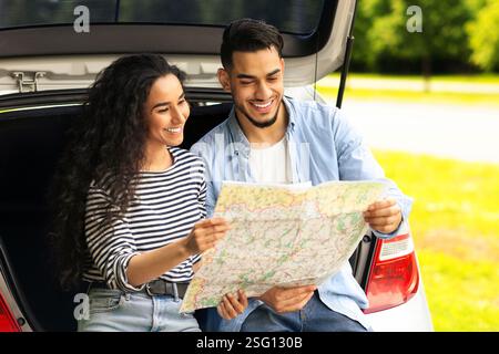 Happy lovers tourists having break while car trip, reading map Stock Photo
