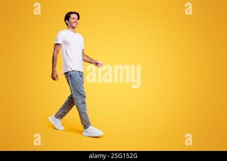 Young bearded man walking isolated on yellow background Stock Photo