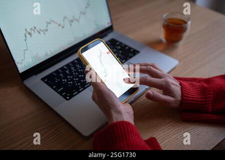 Woman hands analyzing cryptocurrency market trends and graphs on smartphone and laptop Stock Photo