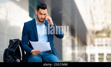 Serious middle eastern businessman having phone conversation on the street Stock Photo