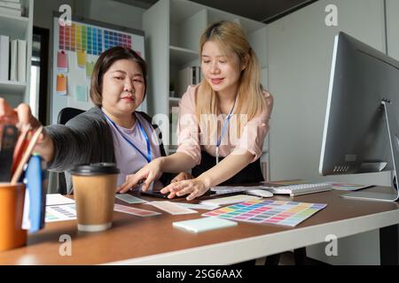 Diverse graphic design team collaborating on color selection in a modern office. Stock Photo