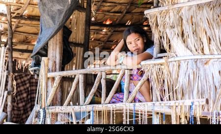 Phangnga, Thailand, 21 January 2025, A local Moken woman sits pensively on a bamboo balcony, enveloped in the tranquil surroundings of Surin Island Stock Photo