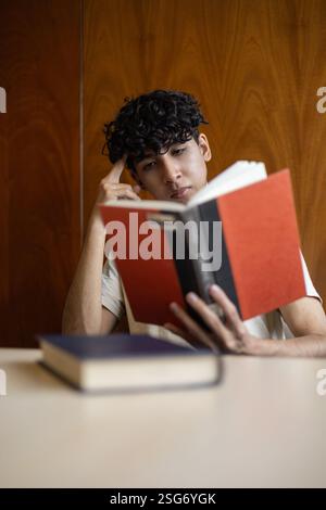A person deeply immersed in reading, lost in a book. Perfect for themes of literature, concentration, relaxation, and personal growth. Stock Photo