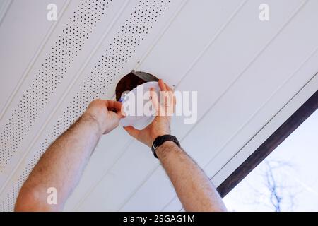 Contractor installs new led lamp at ceiling renovated home improvement. Stock Photo