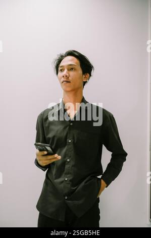 A young man holds his smartphone, ready to connect and communicate. Stock Photo