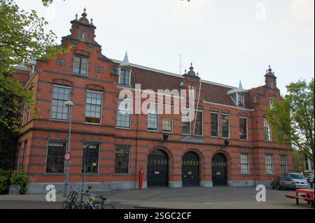 Amsterdam's red brick building with a large metal door could be a historic fire station or a business with convenient bike parking. Stock Photo
