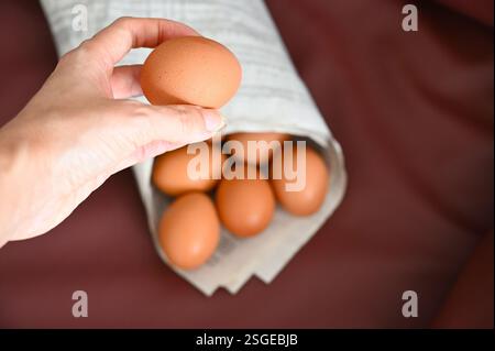 Egg in hand and paper cone on dark background. Stock Photo