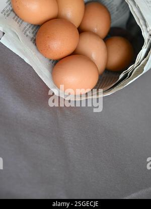 Brown natural eggs in newspaper cone vertical shot. Stock Photo