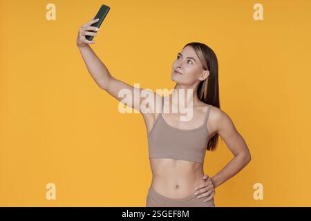 Taking Selfie in Athletic Wear Against Yellow Background Stock Photo