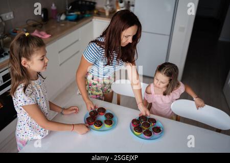 Mother and daughters baking homemade cupcakes in kitchen Stock Photo