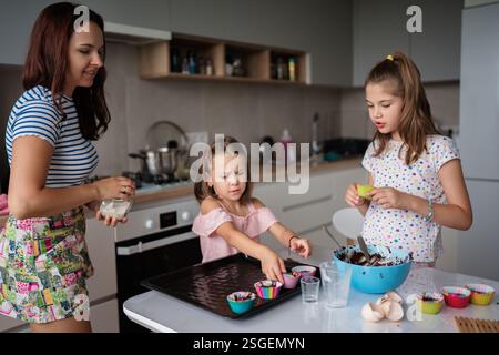 Mother and daughters baking together in modern kitchen Stock Photo