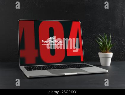 Modern laptop displaying a 404 error page not found message, placed on a dark background next to a small potted plant Stock Photo