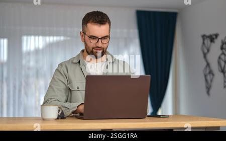 A young man using a laptop while working at home. Stock Photo