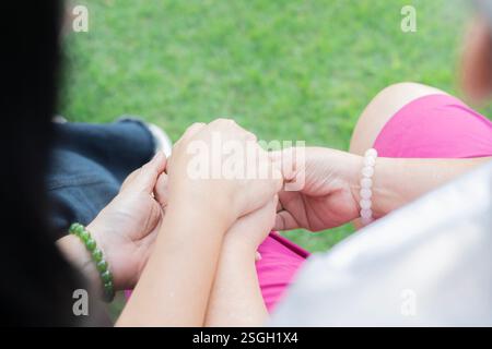 Back view of mother and daughter sit and holding hands while relaxing at park. Selective focus. Stock Photo